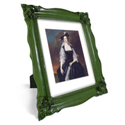 A baroque style picture frame in dark green color with a picture of a woman in historical regal attire displayed within it. The frame is designed for wall and tabletop display.
