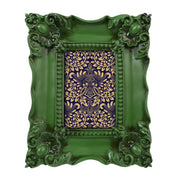 A vintage picture frame with hand-carved floral details in dark green, displayed around a portrait painting.