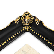 An ornate black picture frame with gold accents, displaying a mountain range artwork.