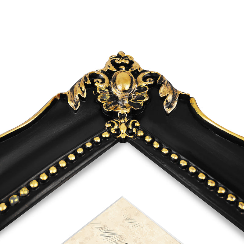 An ornate black picture frame with gold accents, displaying a mountain range artwork.