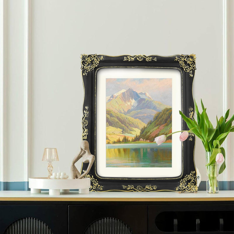 A vintage-inspired black picture frame displays a landscape painting on a shelf with decorative items.