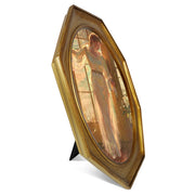 An antique-style octagon picture frame with a brushed gold finish, containing a printed artwork of a woman in a light dress by a window.