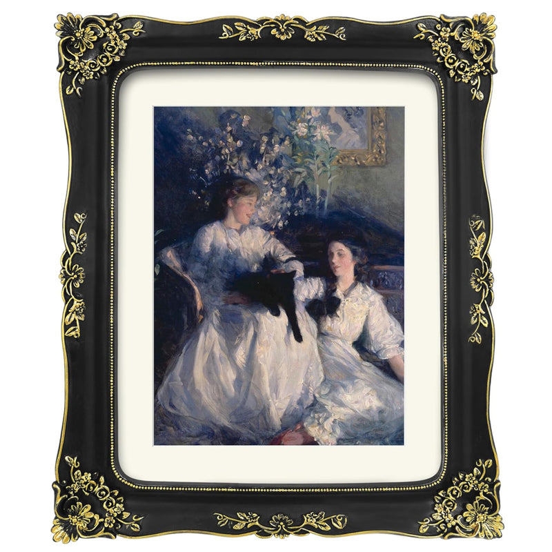 Framed artwork of two women with a black cat, surrounded by flowers, in a decorative gold and black frame.