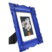 A blue picture frame with a decorative design, displaying a picture of a floral arrangement inside.