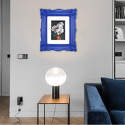 A blue picture frame with a decorative design, displaying a picture of a floral arrangement inside.