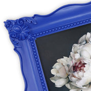 A blue picture frame with a decorative design, displaying a picture of a floral arrangement inside.