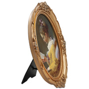 An oval-shaped, gold-colored picture frame with embossed details, containing a framed artwork of a person reading.