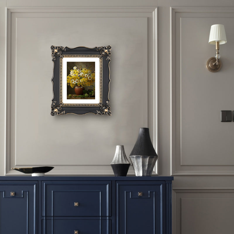 An ornate black picture frame with gold accents, displaying a mountain range artwork.