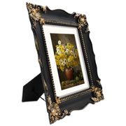 An ornate black picture frame with gold accents, displaying a mountain range artwork.