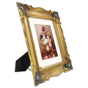 A bronze picture frame with a decorative design, displaying a picture of a floral arrangement inside.