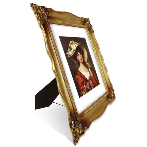 An antique gold picture frame with a white mat, displayed with a picture of a woman in a red dress and a wide-brimmed hat.