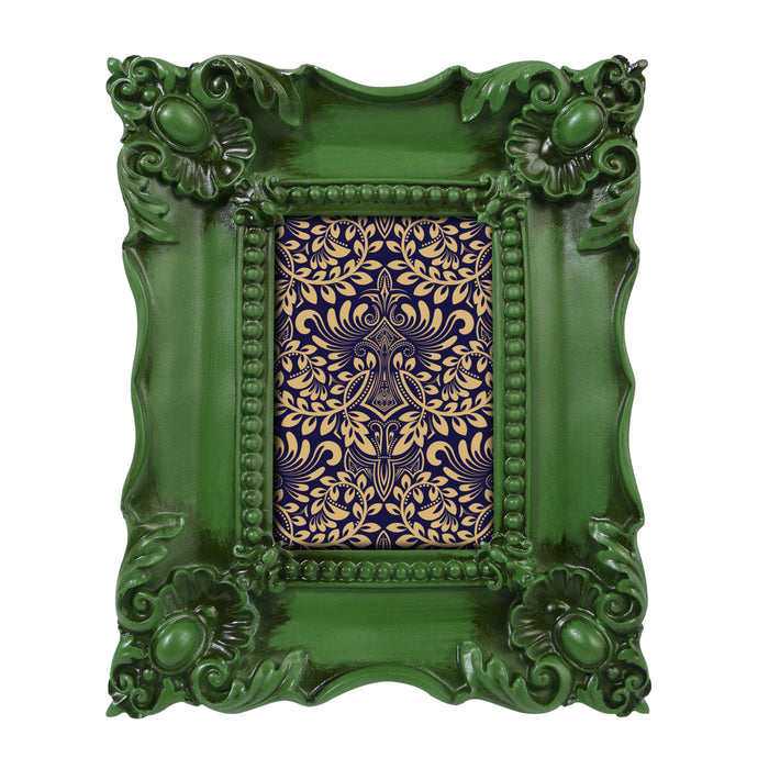 A vintage picture frame with hand-carved floral details in dark green, displayed around a portrait painting.