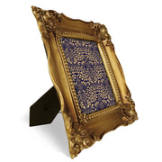 Decorative gold picture frame with intricate patterns on a white background.