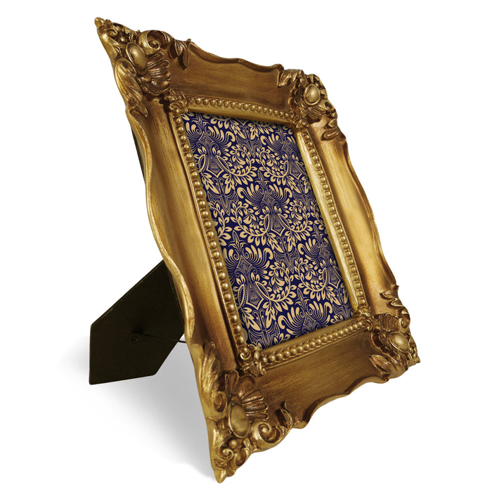 Decorative gold picture frame with intricate patterns on a white background.