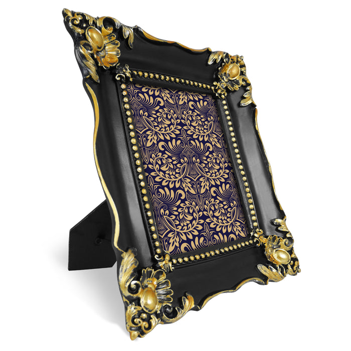 Decorative black and gold picture frame with intricate patterns on a white background.