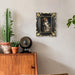 Decorative black frame with a dog portrait on a wall above a wooden cabinet with plants.