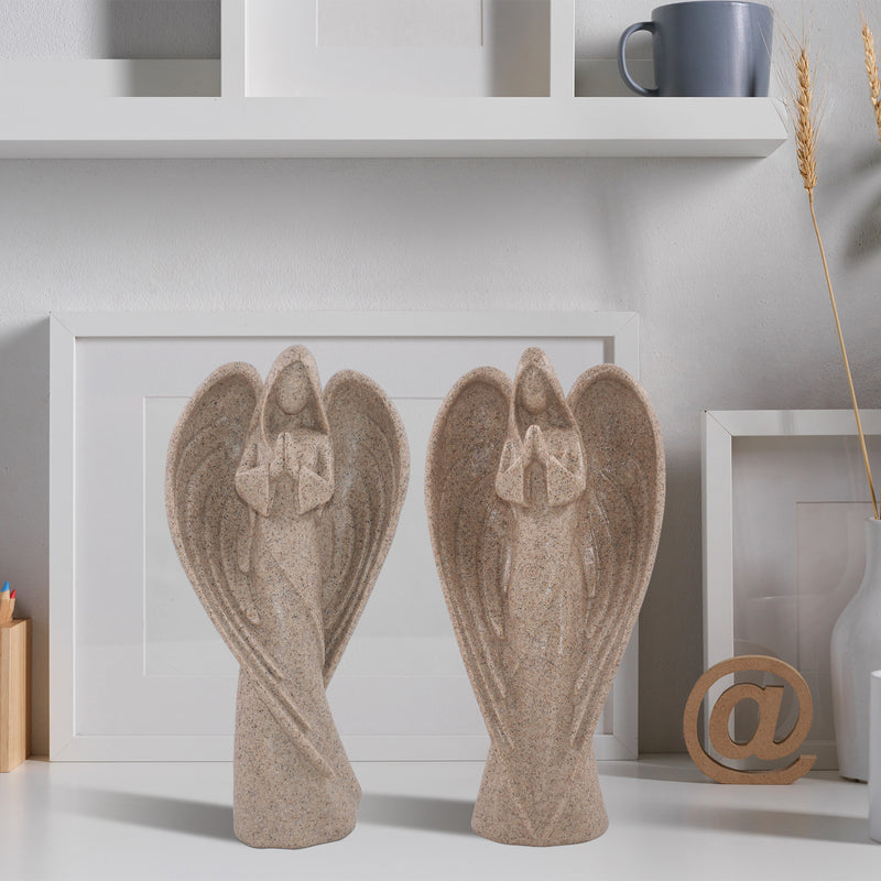 Two angel figurines on a shelf with a neutral background
