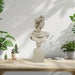 Bust of a classical figure on a wooden table with potted plants.