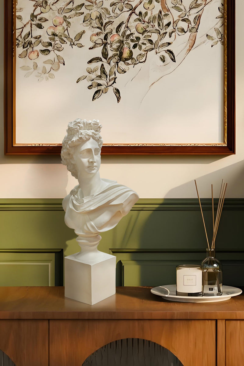 Decorative setup with busts, artwork, and a wooden cabinet.