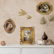 Decorative wall with gold-framed artworks and wall art on a beige wall.