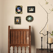 Decorative wall with framed pictures of animals, a wooden chair, and candle holders.