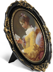Black and gold oval picture frame with ornate scroll and shell carvings, angled view showing fold-out easel back stand