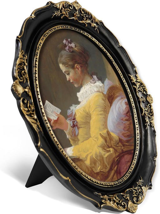 Black and gold oval picture frame with ornate scroll and shell carvings, angled view showing fold-out easel back stand