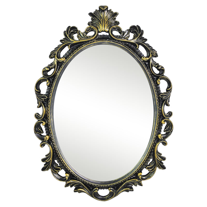 An oval mirror with a scroll design in an antique black with gold finish, reflecting a well-lit interior room.