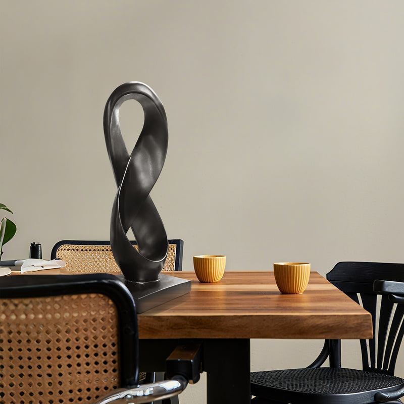 Modern black sculpture on a wooden table with chairs in a room setting