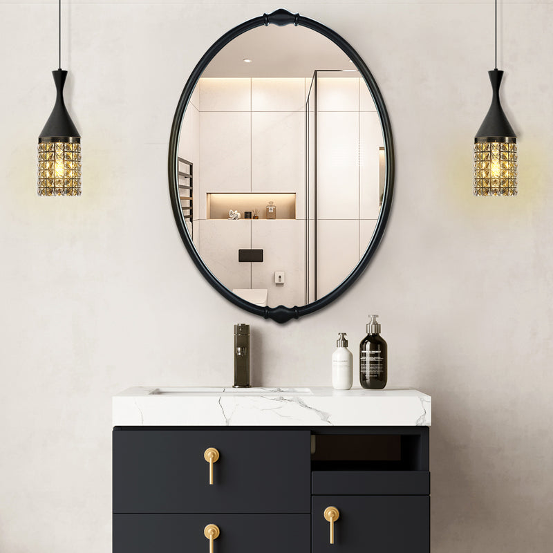 An oval-shaped mirror with a traditional frame in a bathroom setting, reflecting a modern shower stall and bathroom decor.