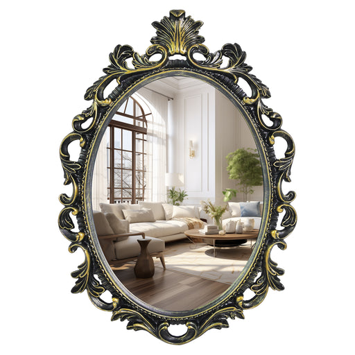 An oval mirror with a scroll design in an antique black with gold finish, reflecting a well-lit interior room.