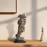 A bronze sculpture of a thinker's face, depicting a silent, reflective pose, is placed on a black base.