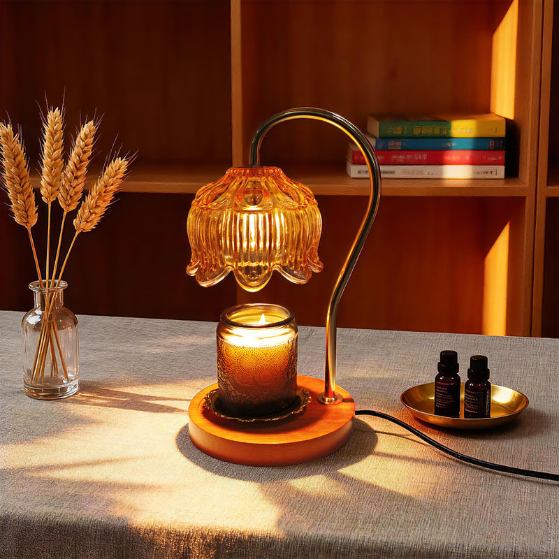 Small table wax warmer lamp with a warm glow on a surface, surrounded by books and a vase of wheat.