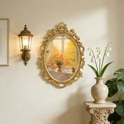 Decorative wall mirror with gold frame on a wall next to a lamp and plant.