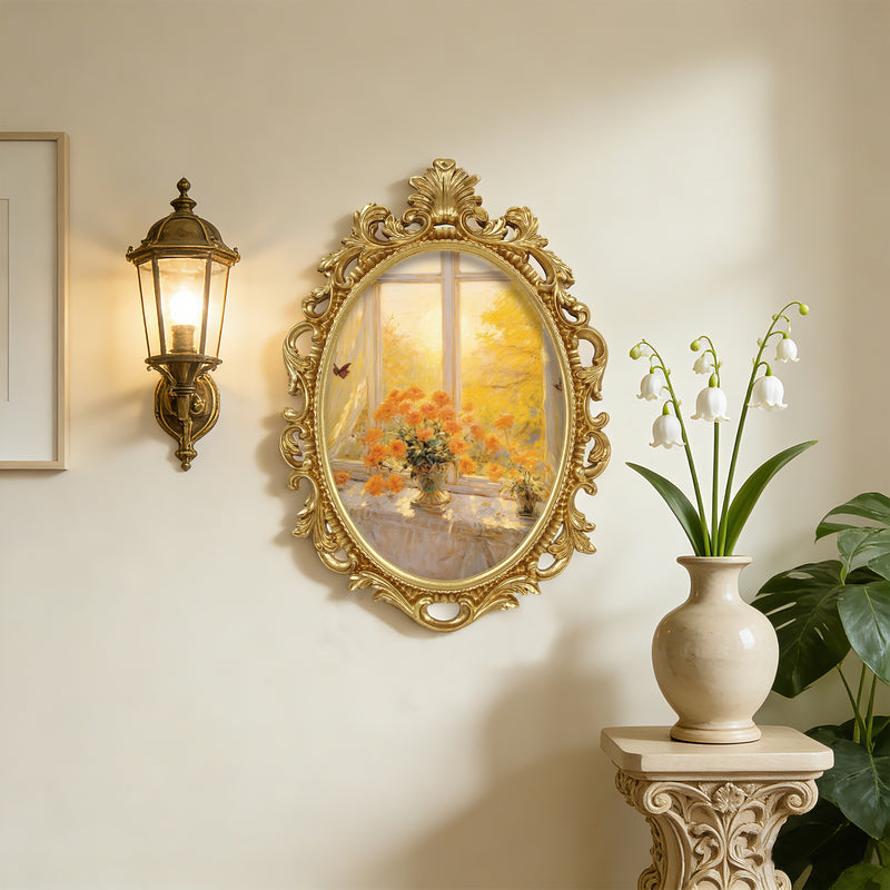 Decorative wall mirror with gold frame on a wall next to a lamp and plant.