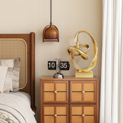 Decorative gold sculpture on a wooden nightstand next to a bed with wicker headboard.