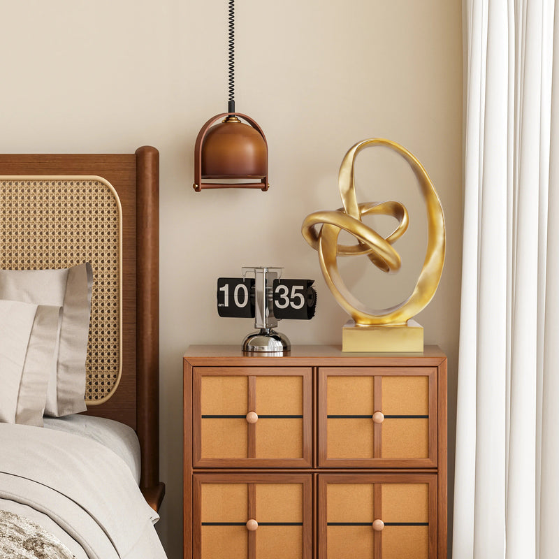 Decorative gold sculpture on a wooden nightstand next to a bed with wicker headboard.