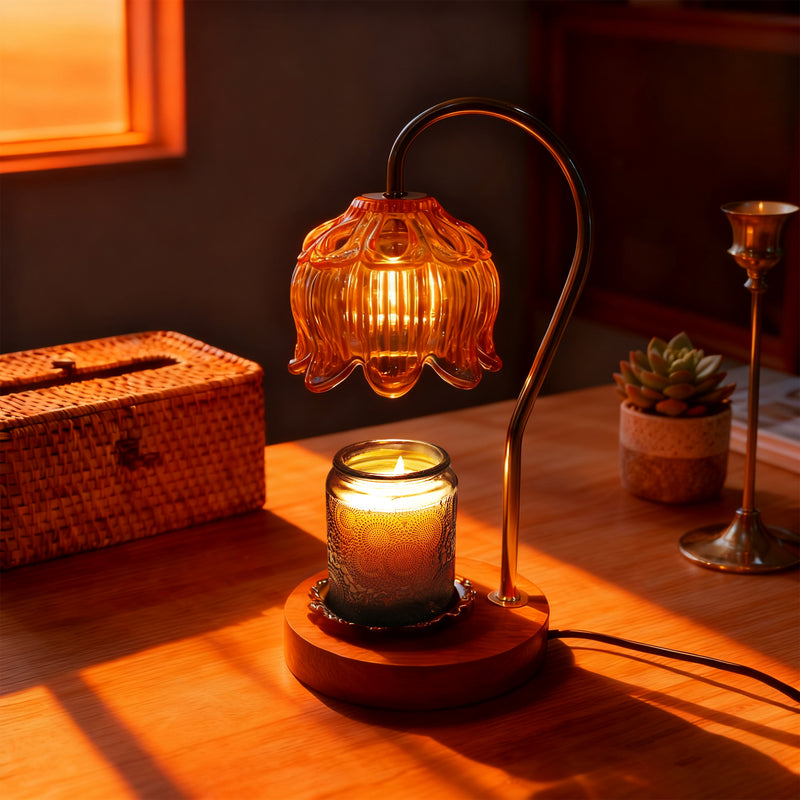 Decorative candle warmer lamp with a warm glow on a wooden surface, surrounded by a wicker box and a small plant.