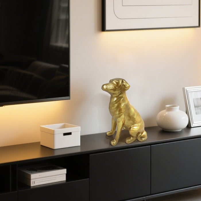 Gold dog figurine on a black entertainment console with a TV and decor items.