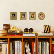 Bookshelf with books and decorative items against a wall with framed pictures.