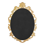 An oval mirror with a scroll design in an antique gold finish, reflecting a well-lit interior room.