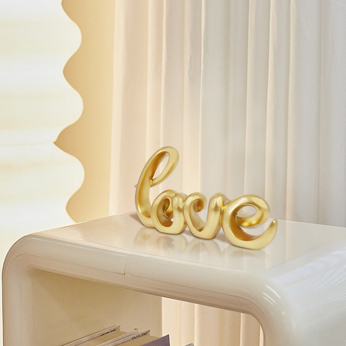 A gold-colored sculpture in the form of the word 'LOVE' in a cursive script, designed for tabletop decor.