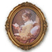 An oval-shaped, gold-colored picture frame with embossed details, containing a framed artwork of a person reading.