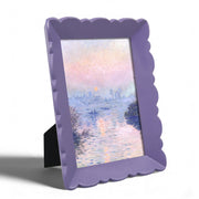 Purple scalloped frame with a painting of a sunset over water on a white background