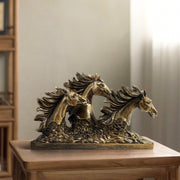 A bronze sculpture of three horses in mid-gallop with flowing manes, positioned on a flat base.