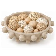 A round beige decorative bowl with raised pom-pom details around the rim, filled with assorted natural-fiber and textured decorative balls in neutral beige, cream, and tan tones, on a white background.