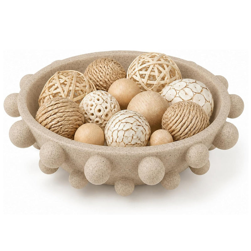 A round beige decorative bowl with raised pom-pom details around the rim, filled with assorted natural-fiber and textured decorative balls in neutral beige, cream, and tan tones, on a white background.