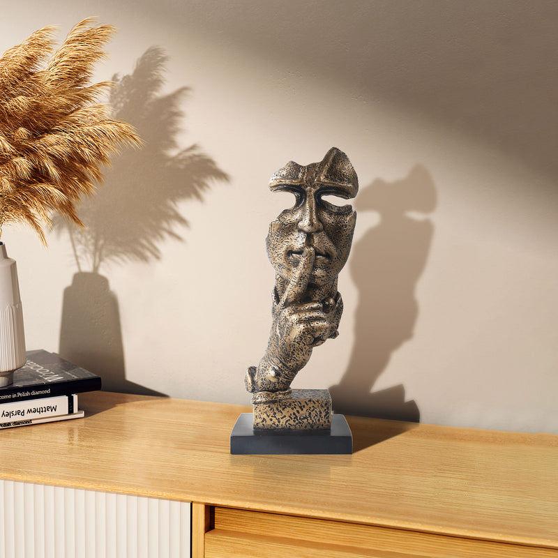 A bronze sculpture of a thinker's face, depicting a silent, reflective pose, is placed on a black base.