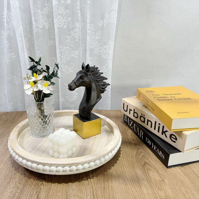 A dark brown horse sculpture standing on a solid golden base.