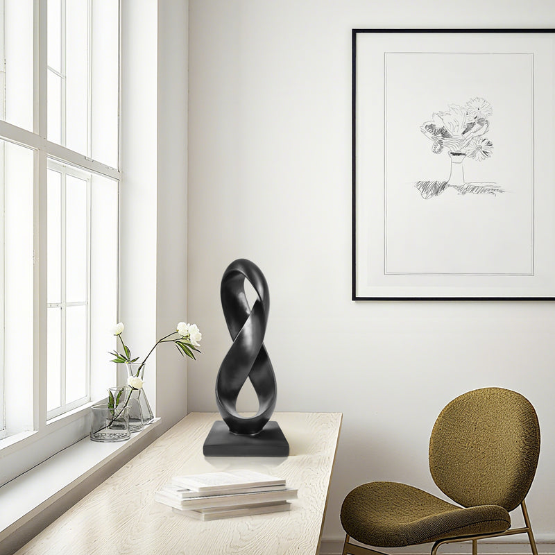 Modern interior with a black abstract sculpture on a table, a green chair, and a framed artwork on the wall.